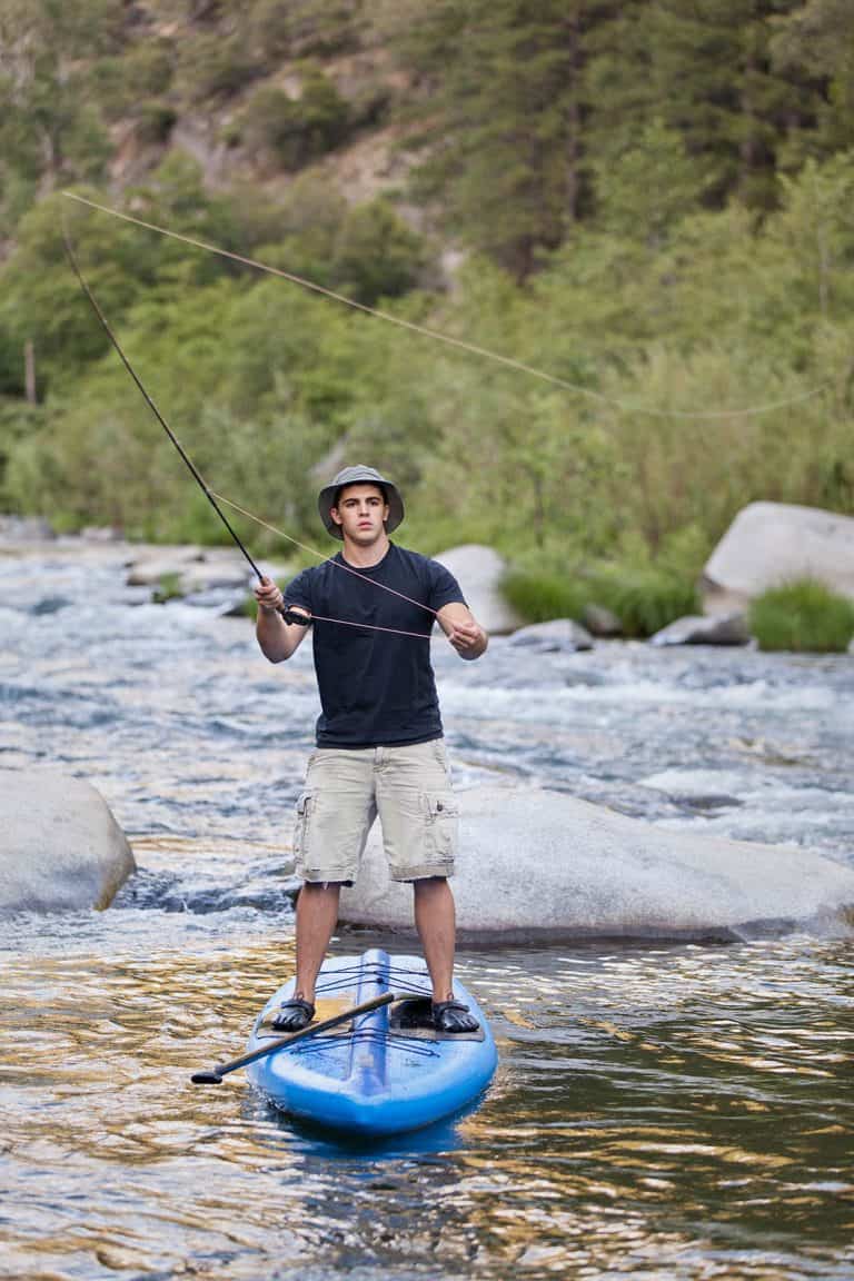 A young man flyfishing from a paddle board in a the rapids of the Feather River in Northern California.