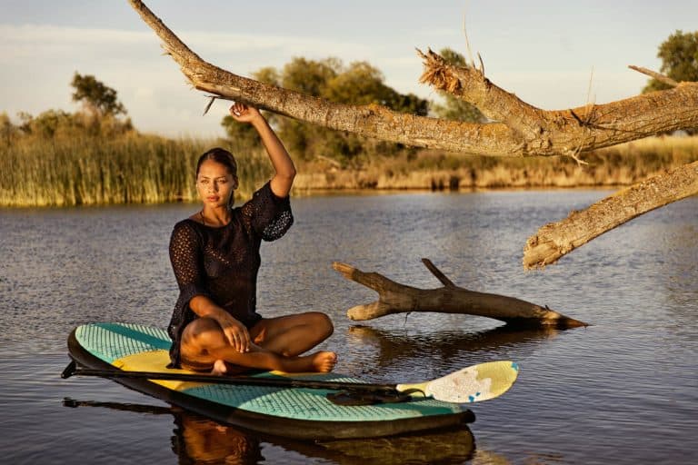 A young, attractive woman relaxing on a paddle board on a small lake in Northern California.