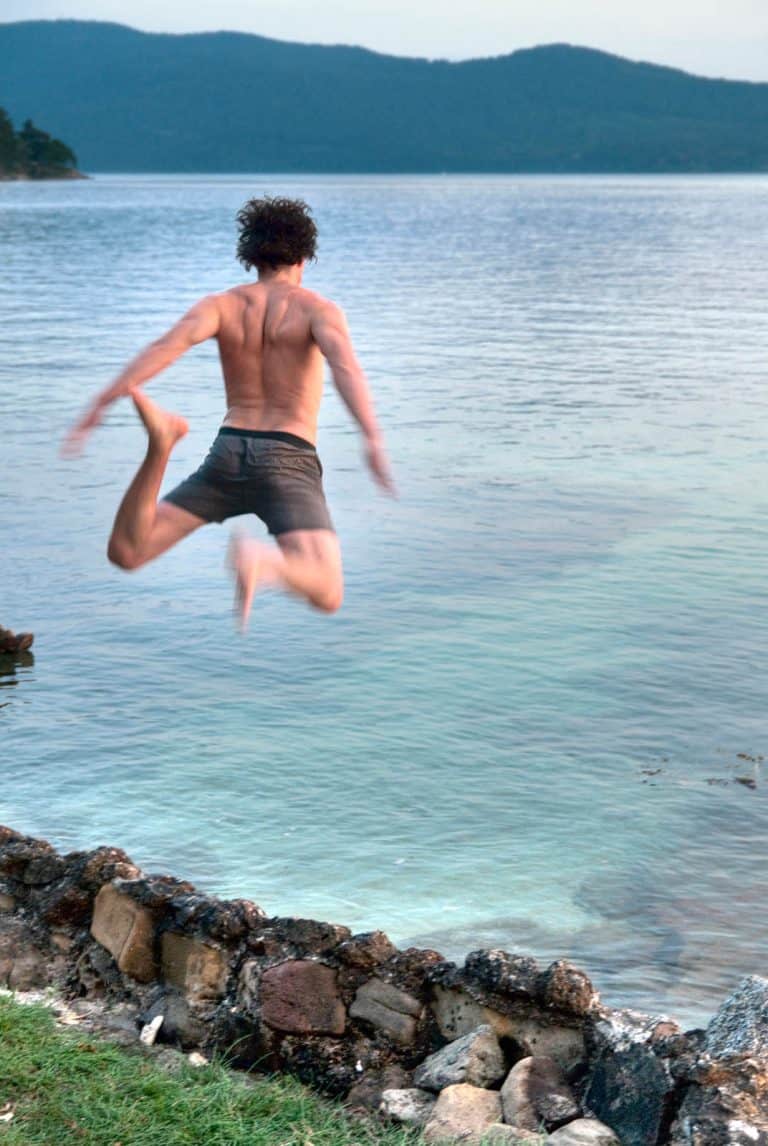 Jumping over a rock wall into the ocean.