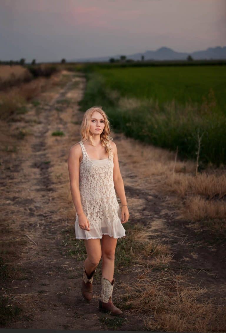 Country girls wearing a Free People Slip and cowboy boots walking through a field on a farm.