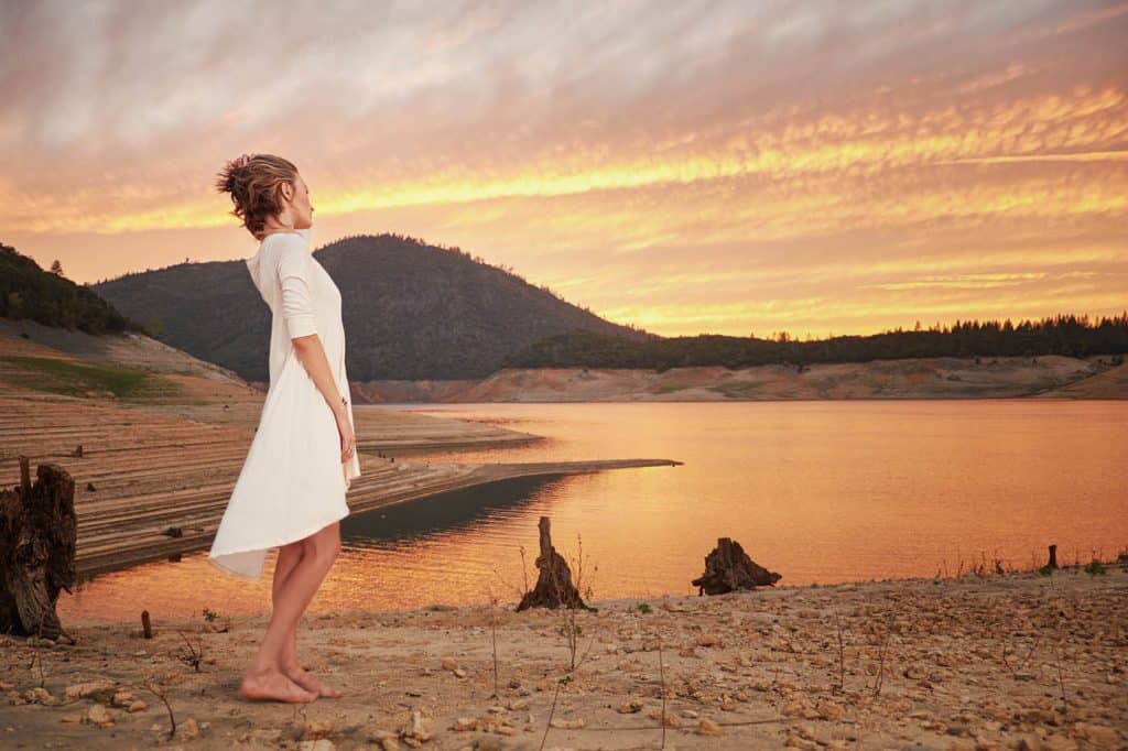 Woman watching the sunset on the shore of a remote mountain lake