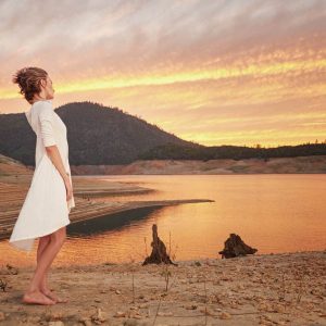 Woman watching the sunset on the shore of a remote mountain lake